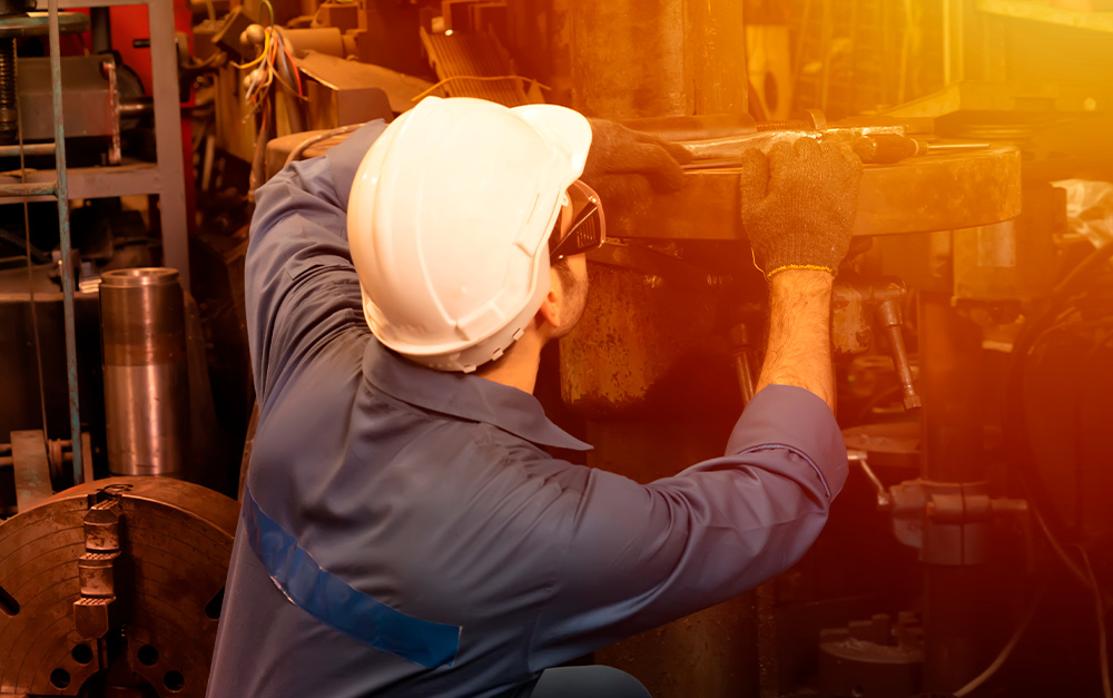 Imagem de um dos funcionários da Hachi Metal Mecânica realizando a manutenção de uma peça industrial.